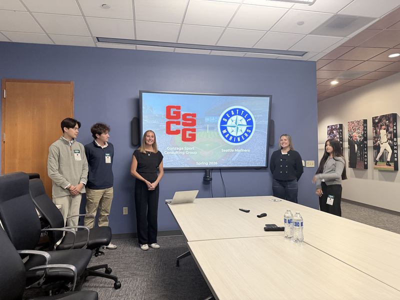 Students presenting beside a screen showing the GSCG and Seattle Mariners logos.