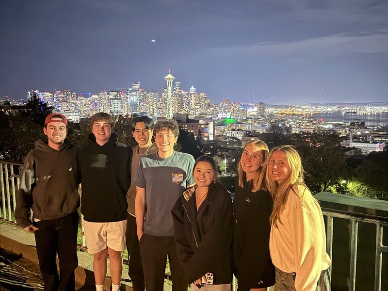 Students in front of the Seattle skyline at night.