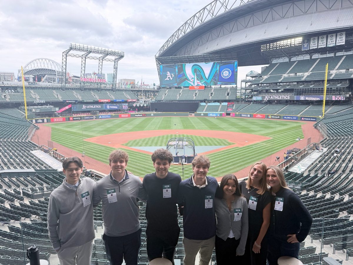 Seven students on the warning track at T-Mobile Park with the empty stands behind them.