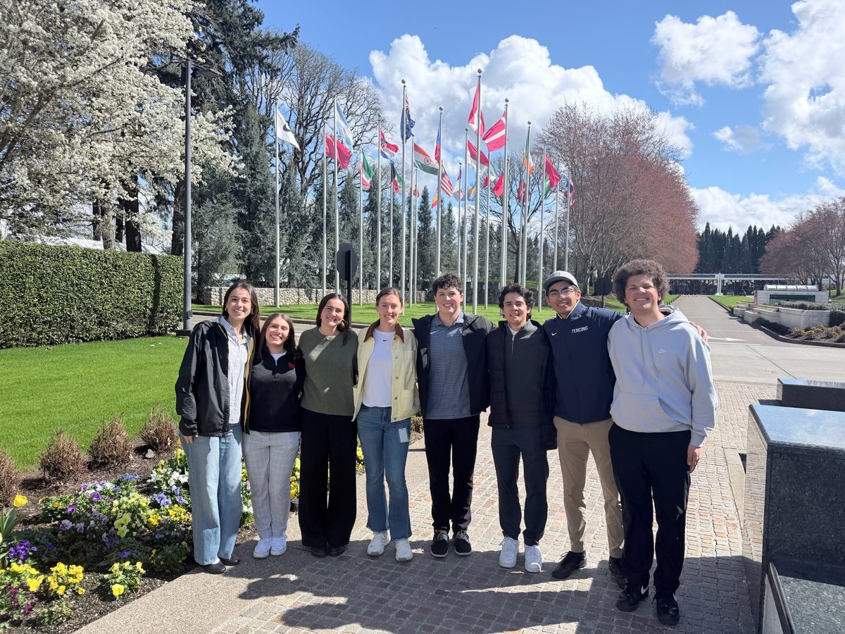 Nine students on the Nike campus in Portland with international flags behind them.