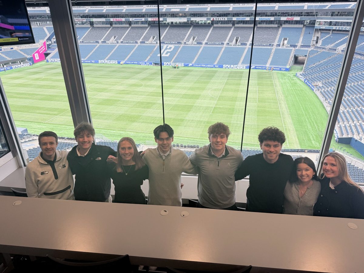 Eight students in a suite above the pitch at Lumen Field in Seattle.